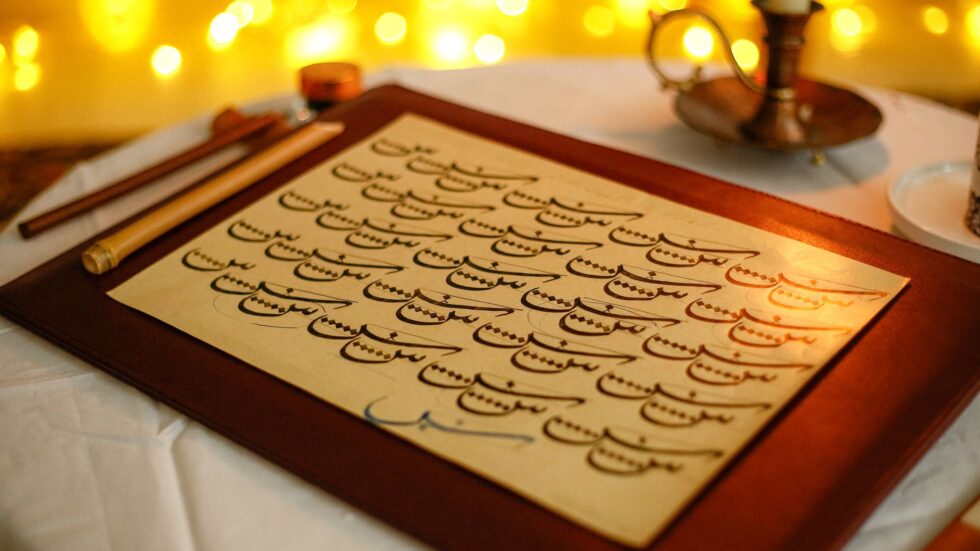 Calligrafia scritta a mano illuminata da una calda luce di candela in un'ambientazione vintage.