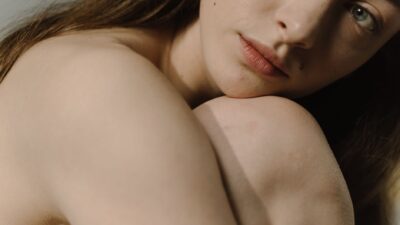 Ritratto ravvicinato di una donna a pelle nuda con sguardo intimo e luce soffusa