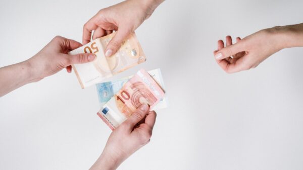 Due mani si scambiano banconote in euro in un momento di transazione economica