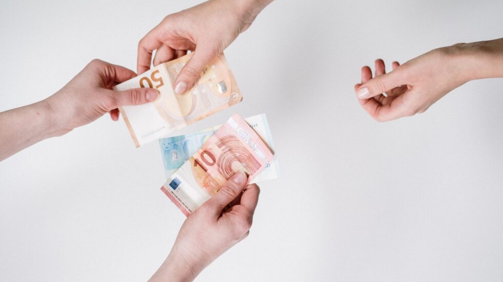 Due mani si scambiano banconote in euro in un momento di transazione economica