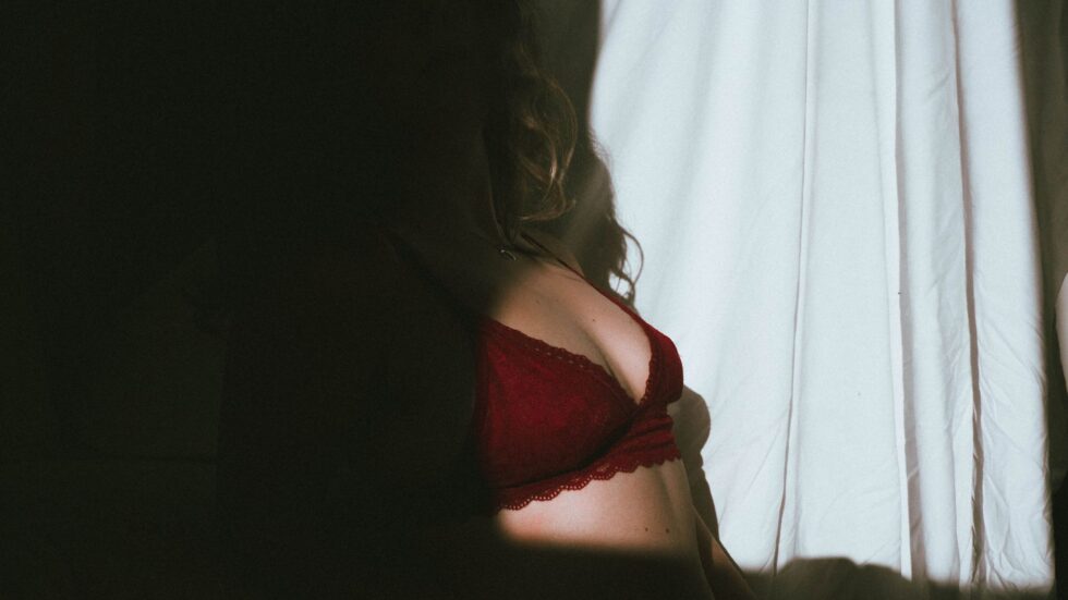 Silhouette femminile in lingerie rossa, giochi di ombre e luce suggestivi