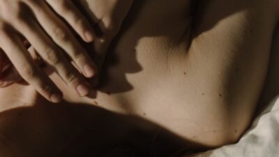 Una mano appoggiata delicatamente sulla pelle, illuminata da una luce naturale soffusa