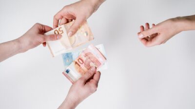 Primo piano di due mani che si scambiano banconote in euro