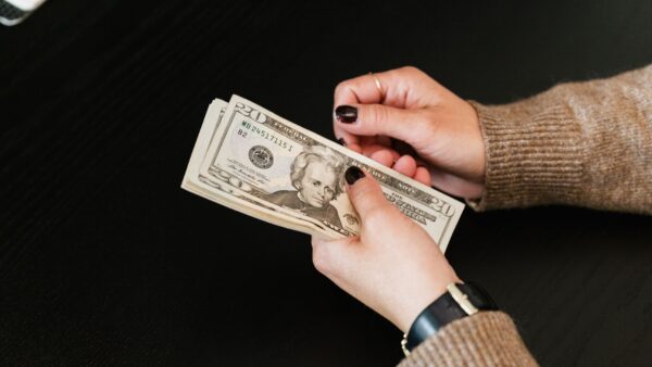 Mani contano una pila di banconote da dollaro su un tavolo scuro