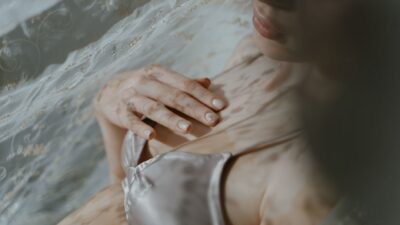 Primo piano di una donna in lingerie sotto un tessuto trasparente, atmosfera sensuale e delicata